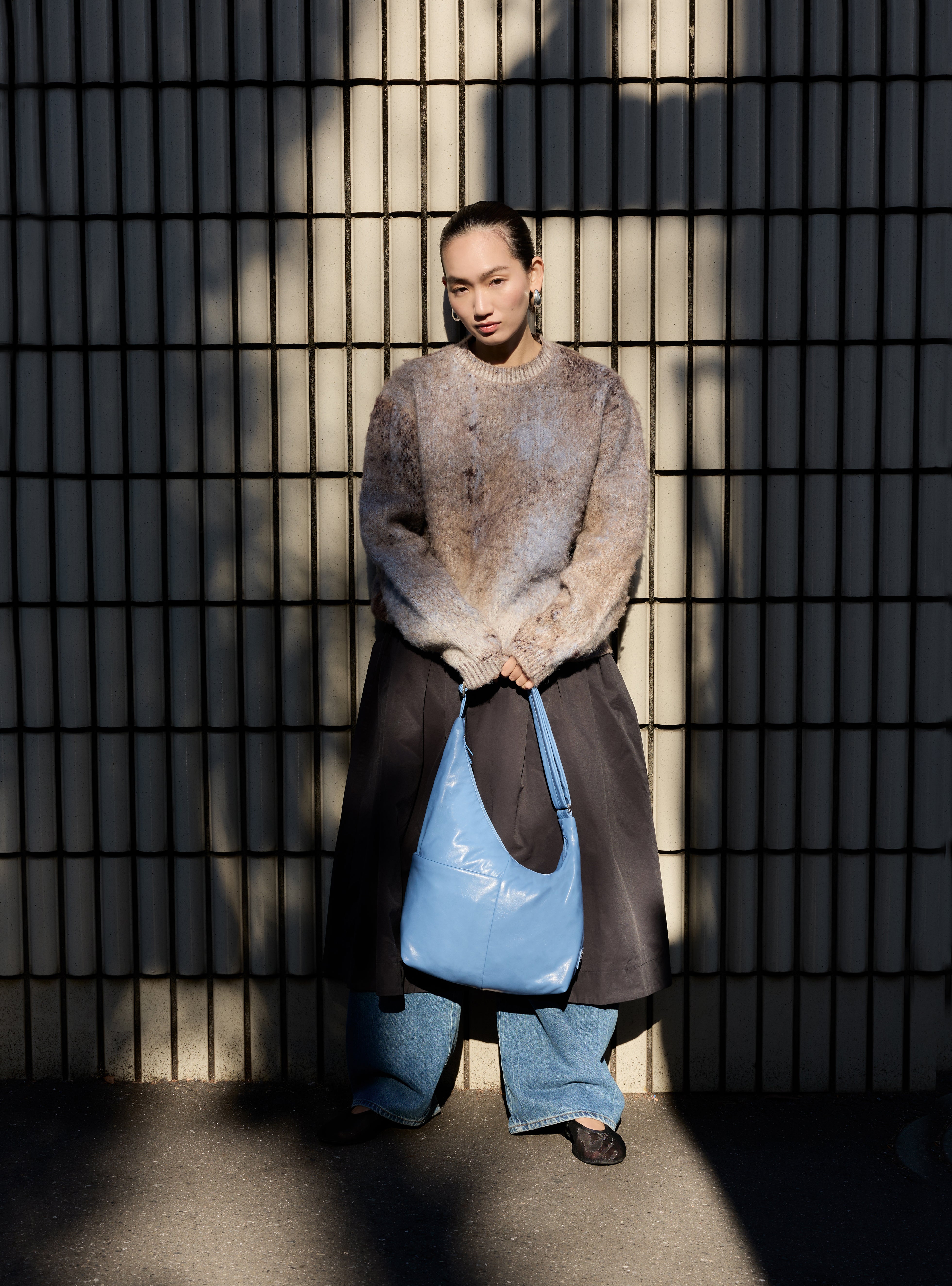 Woman holding the Midi Arc slouchy hobo bag in island blue vegan leather for work, travel and everyday use