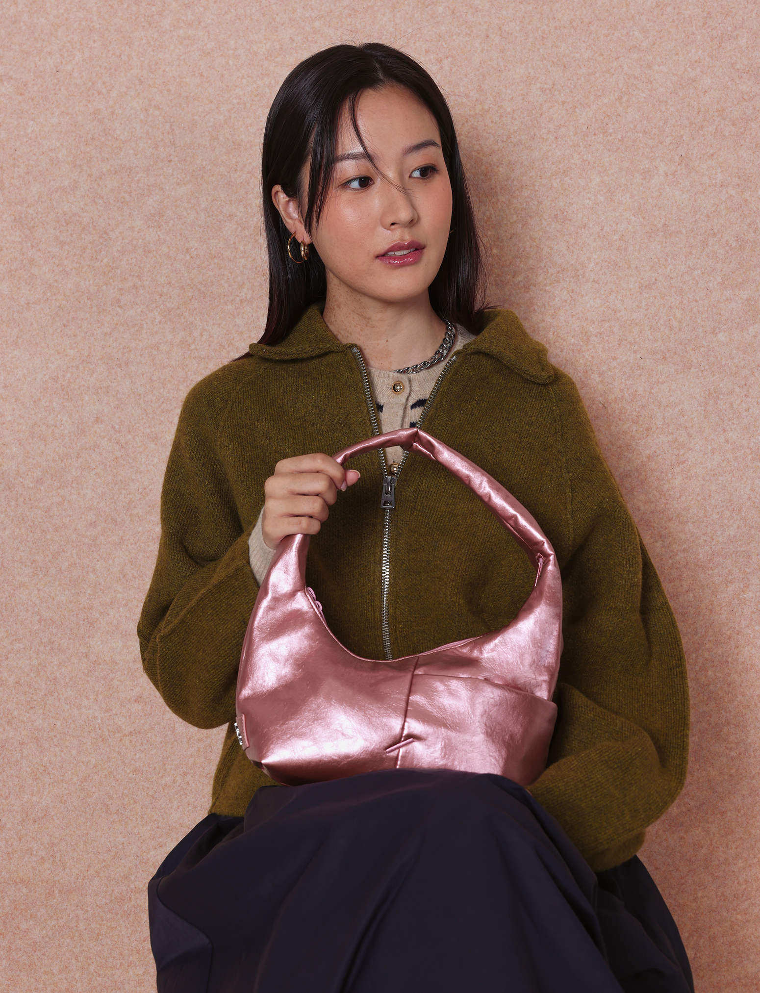 Woman holding the Mini Arc slouchy hobo-style shoulder bag in metallic pink vegan leather for errands, weekends and everyday use