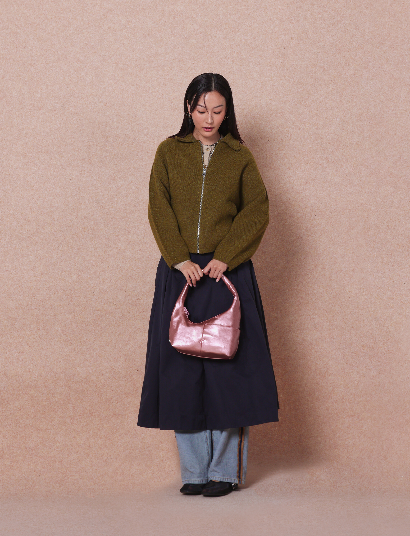 Woman holding the Mini Arc slouchy hobo shoulder bag in metallic pink vegan leather