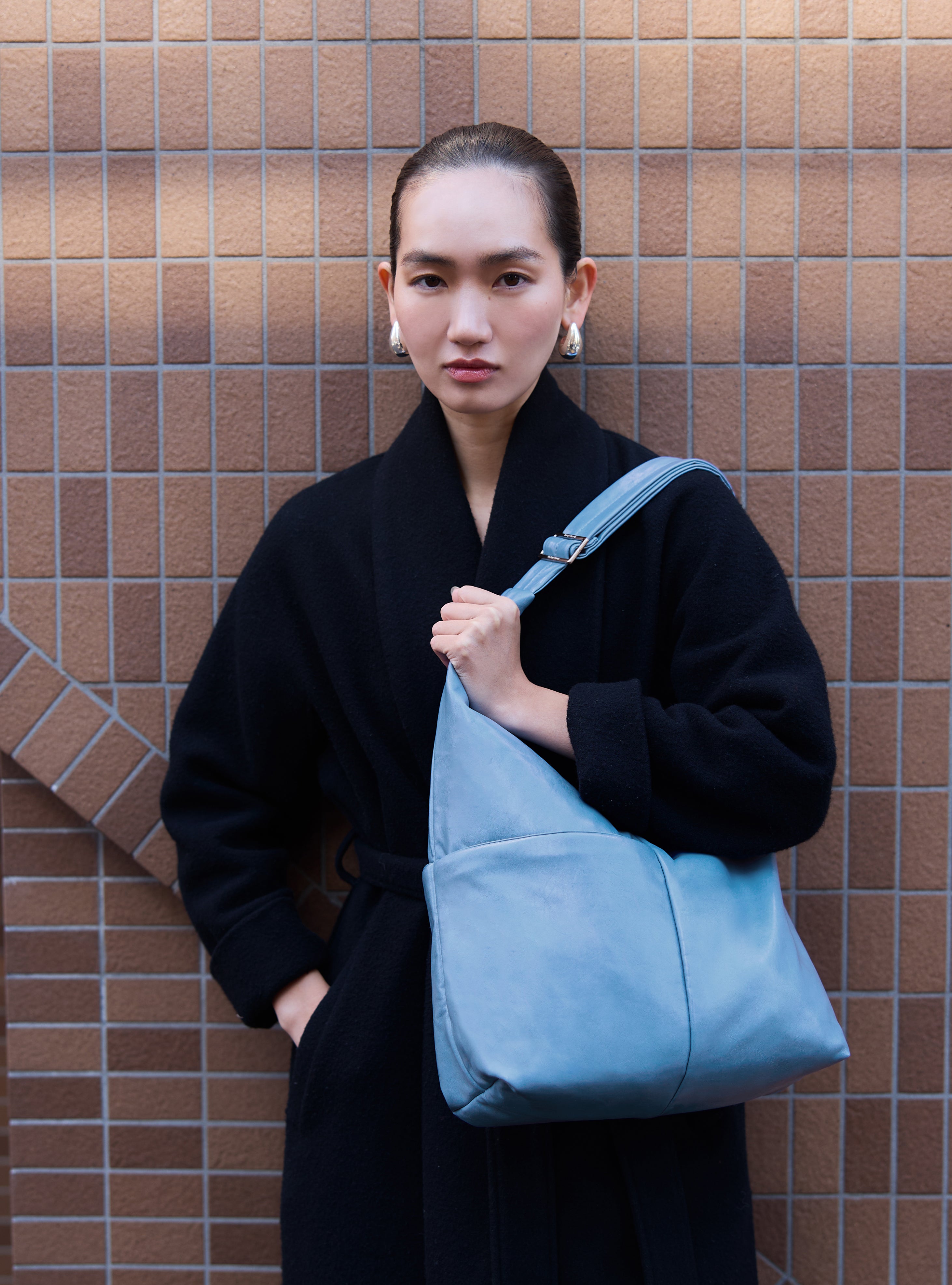 Woman carrying the Midi Arc slouchy hobo bag in island blue vegan leather as shoulder bag