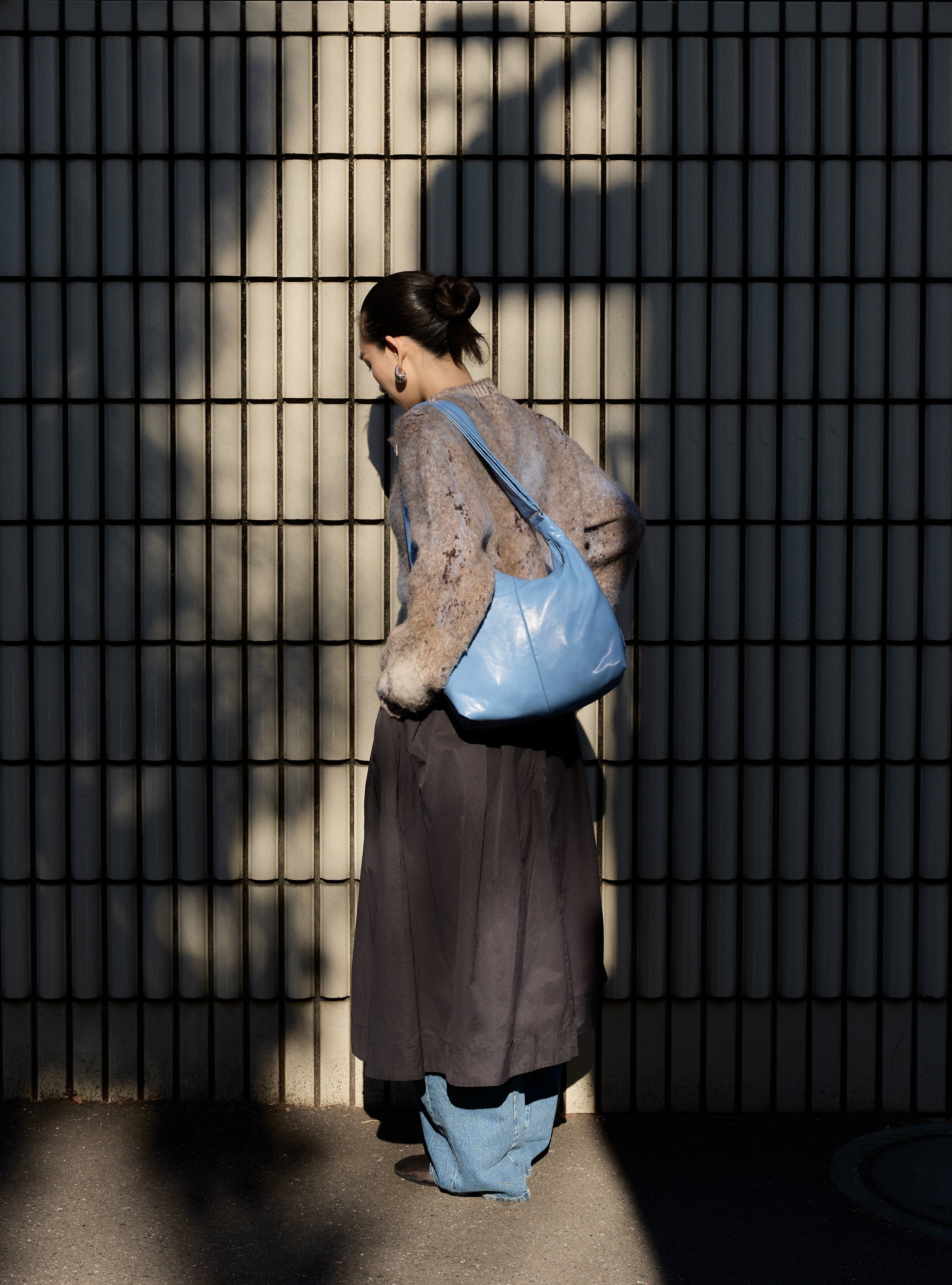 Woman carrying the Midi Arc slouchy hobo bag in island blue vegan leather as shoulder bag