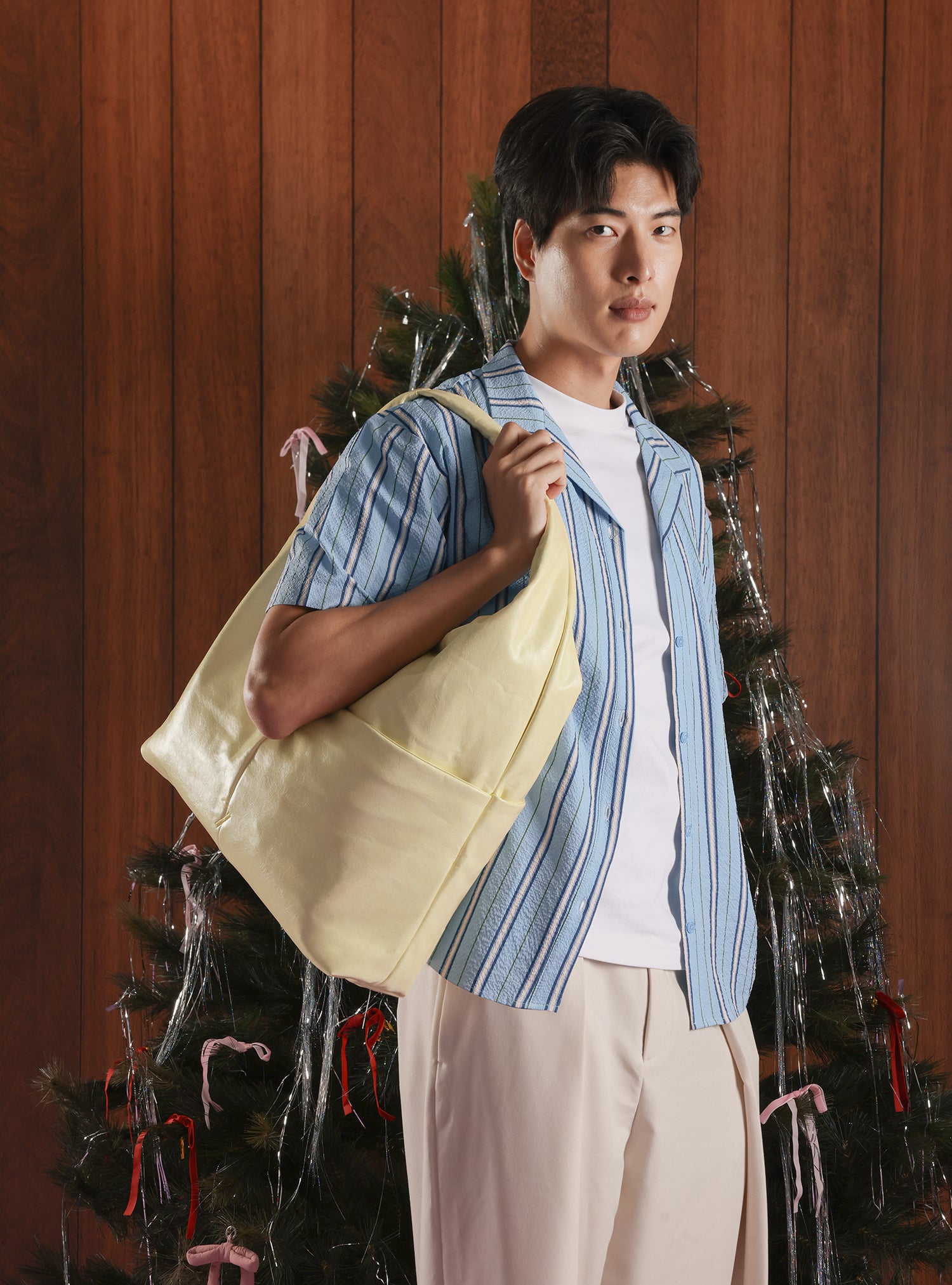 Man carrying the Arc slouchy hobo-style bag in pale yellow vegan leather as a shoulder bag for work, travel and everyday use